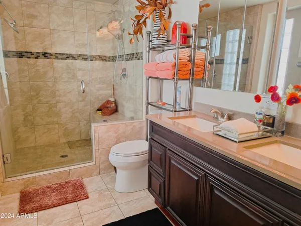 a bathroom with a granite countertop sink a toilet a mirror and shower