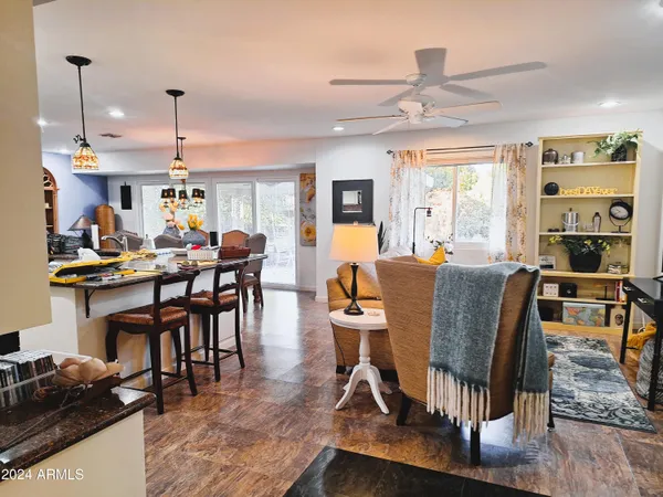 a living room with furniture kitchen view and a large window