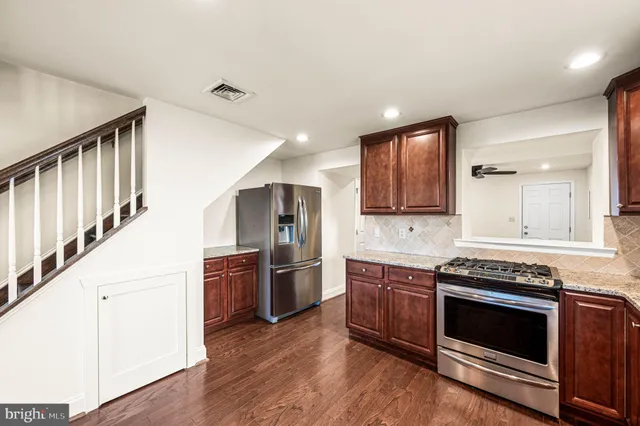 a kitchen with stainless steel appliances kitchen island granite countertop a stove a sink and a refrigerator