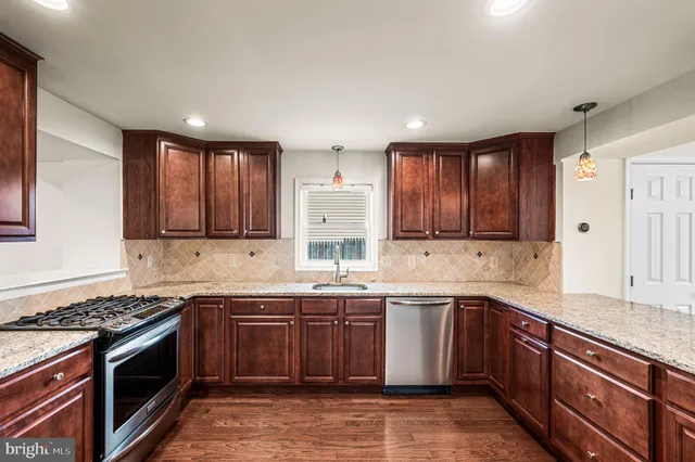 a kitchen with stainless steel appliances granite countertop wooden cabinets stove top oven and sink