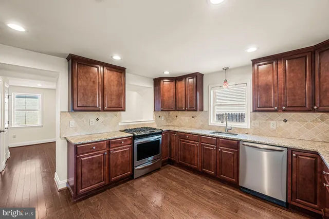 a kitchen with stainless steel appliances granite countertop wooden cabinets a sink and dishwasher a oven with wooden floors