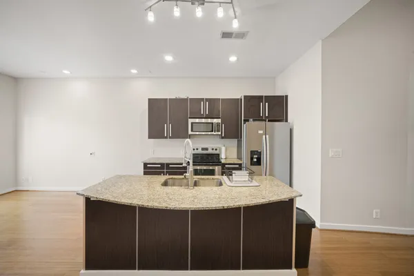 a kitchen with kitchen island a sink stove and refrigerator with wooden floor