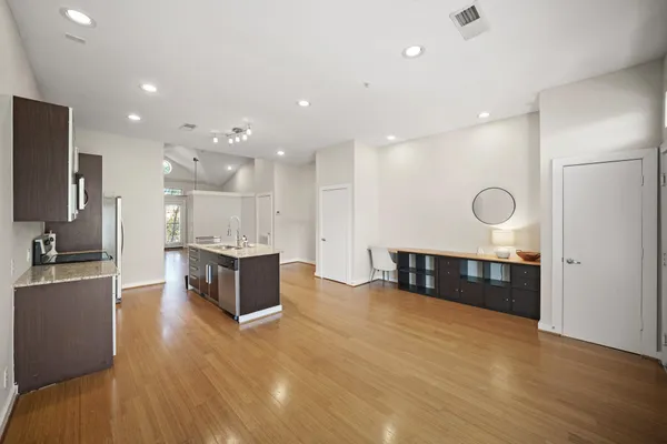 a large white kitchen with a large counter top stainless steel appliances and wooden floor