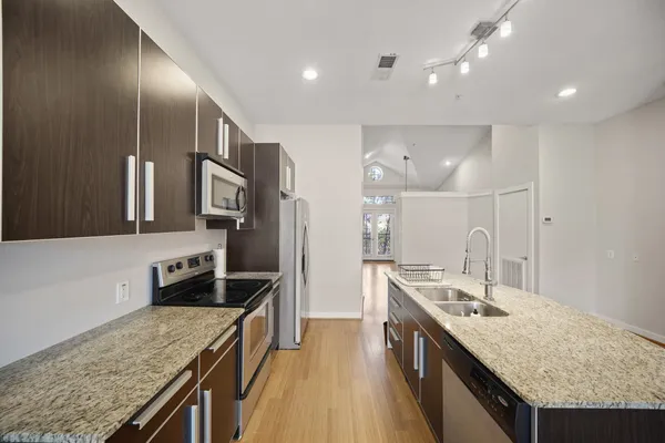 a kitchen with stainless steel appliances granite countertop wooden cabinets and sink