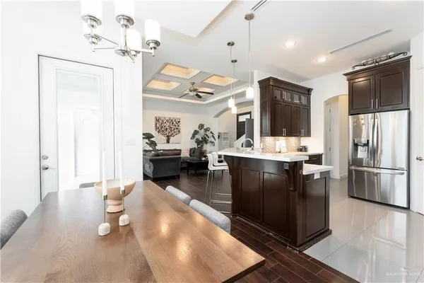 a kitchen with stainless steel appliances kitchen island granite countertop a refrigerator a stove and a sink with wooden floor