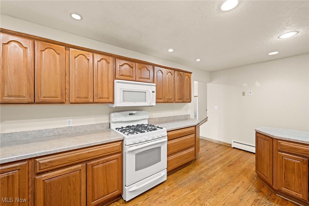 7590 Little Mountain Road Mentor, OH 44060 - Photo 16 of 40 Kitchen featuring recessed lighting, white appliances, light wood-style flooring, and a baseboard radiator