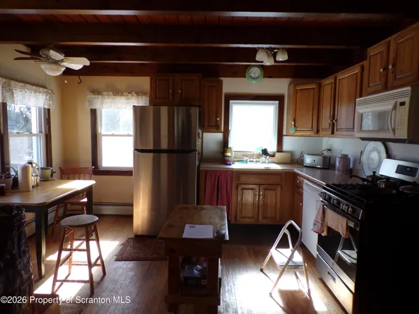 a kitchen with a refrigerator a stove a sink and dishwasher with wooden floor
