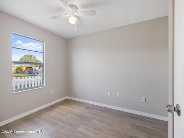 an empty room with a window and ceiling fan