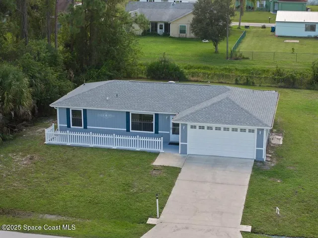 a aerial view of a house next to a yard with big trees