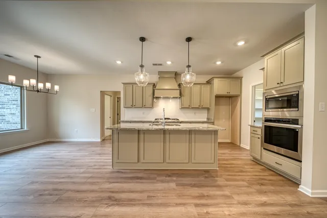 a large kitchen with stainless steel appliances kitchen island granite countertop a stove a sink and a refrigerator
