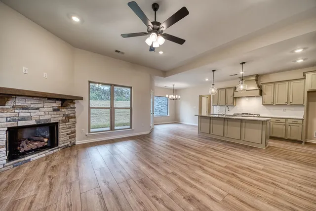 a large kitchen with stainless steel appliances granite countertop a stove a sink dishwasher and a fireplace with wooden floor