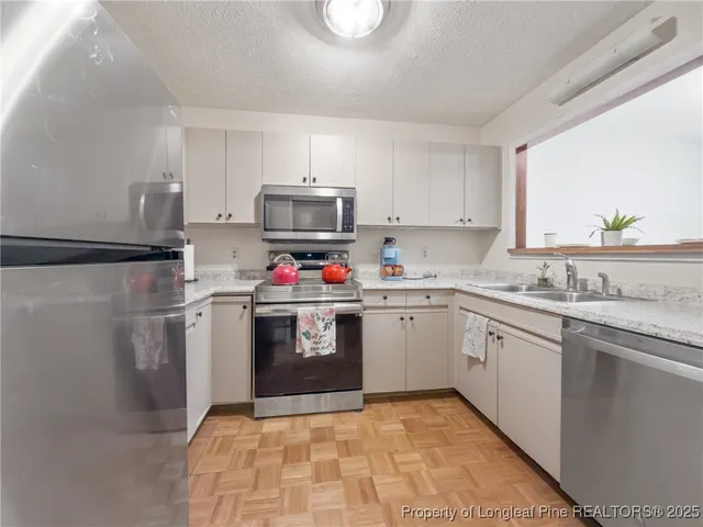 a kitchen with white cabinets stainless steel appliances and sink