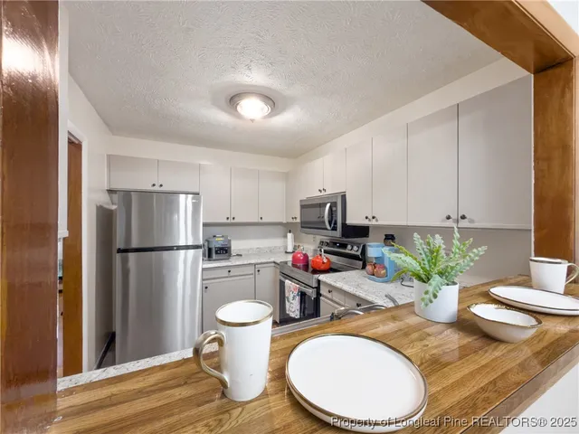 a kitchen with stainless steel appliances a refrigerator a sink a stove a dining table and chairs