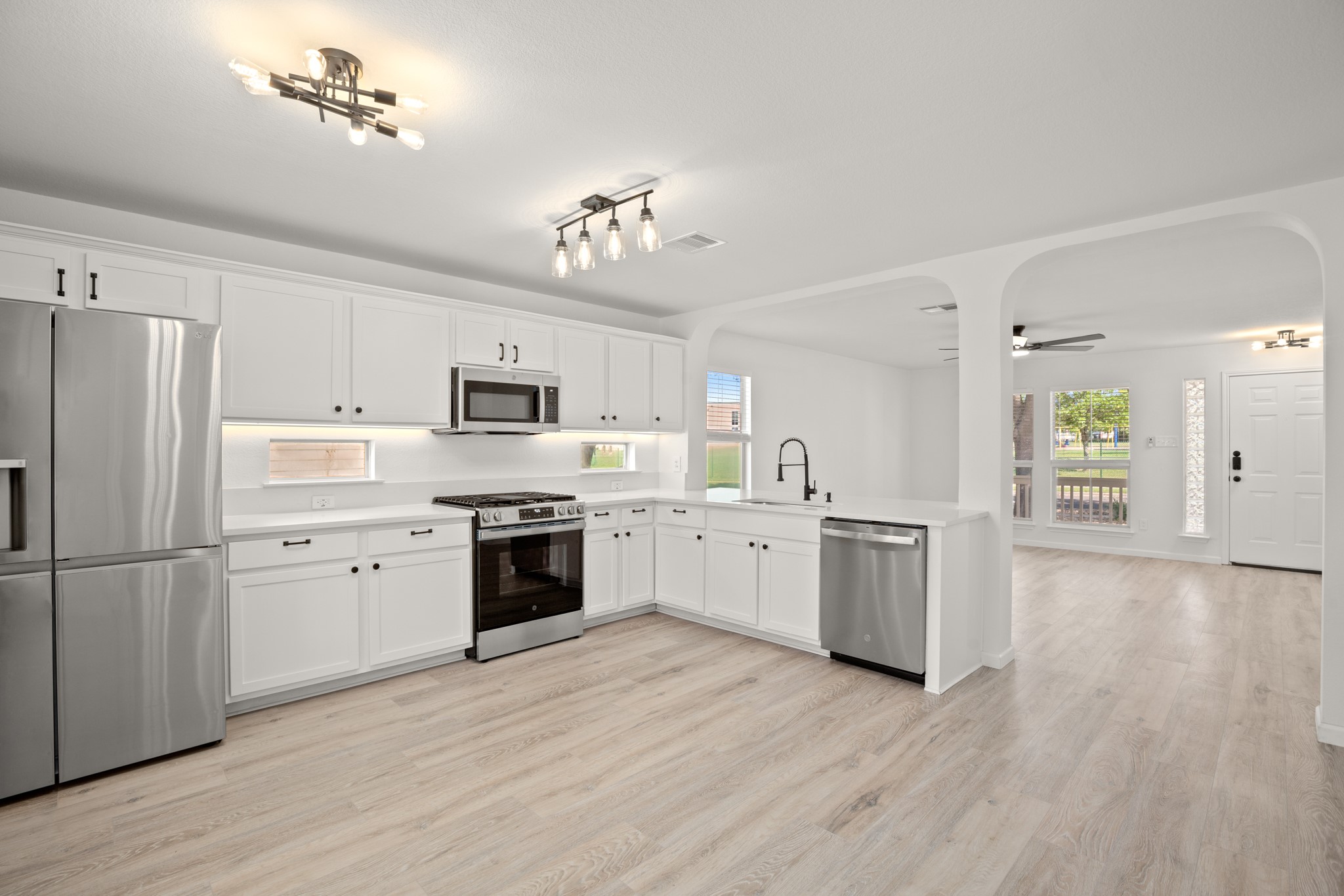 360 Sampson Kyle, TX 78640 - Photo 3 of 36 Bright kitchen featuring white quartz countertops, white cabinetry, stainless steel appliances, light wood-finish flooring, and a contemporary ceiling fixture