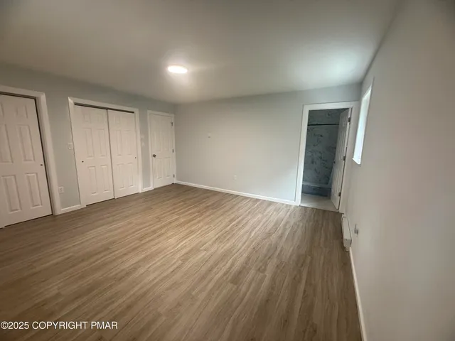 a view of an empty room with wooden floor and closet