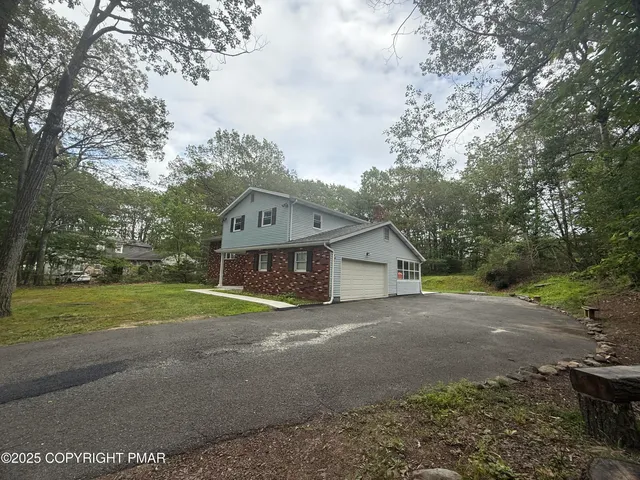 a view of a house with a yard and large trees