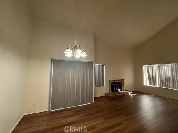 an empty room with wooden floor fireplace and windows