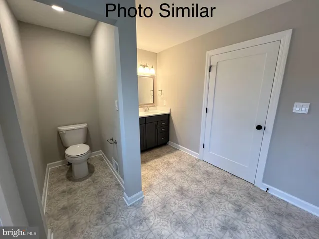 a bathroom with a granite countertop toilet and a sink