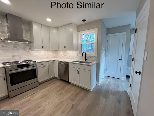 a kitchen with stainless steel appliances white cabinets and wooden floor