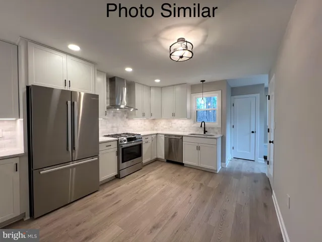 a kitchen with stainless steel appliances granite countertop a refrigerator a stove and a wooden floors