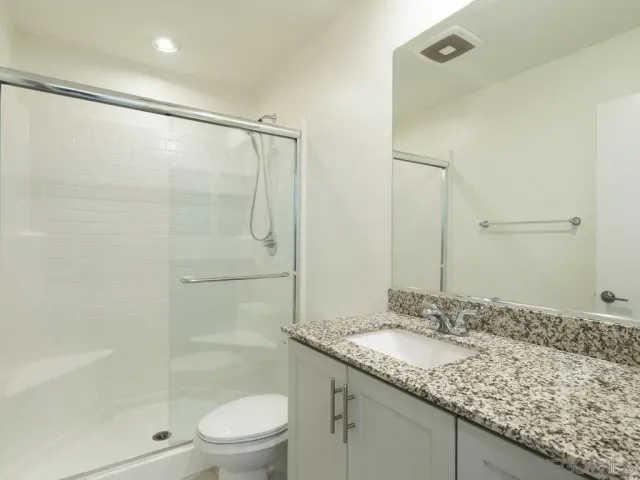 a bathroom with a granite countertop sink a toilet and shower