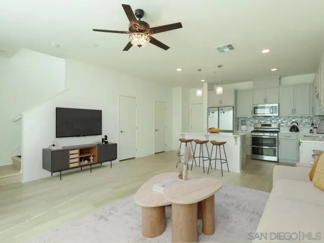 a living room with furniture and a flat screen tv with kitchen view