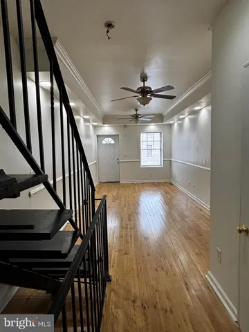 a view of an empty room with wooden floor and stairs