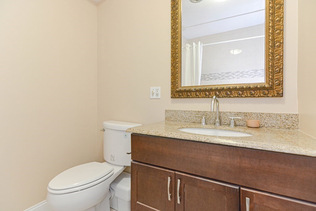 59 Brainerd Road, Unit 410 Boston, MA 02134 - Photo 27 of 41 a bathroom with a granite countertop toilet sink and mirror