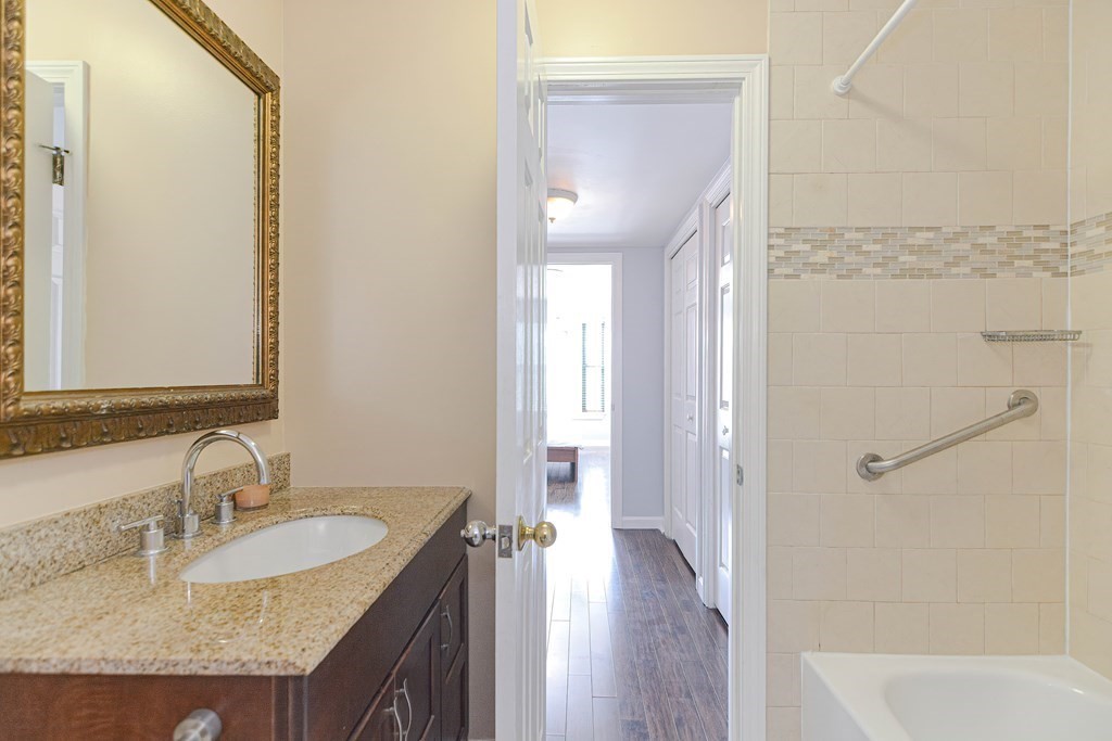 59 Brainerd Road, Unit 410 Boston, MA 02134 - Photo 28 of 41 a bathroom with a granite countertop sink a mirror and a bathtub