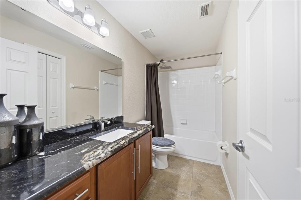 4066 Sundance Pl Loop Mulberry, FL 33860 - Photo 16 of 28 a bathroom with a granite countertop sink a toilet a mirror and shower