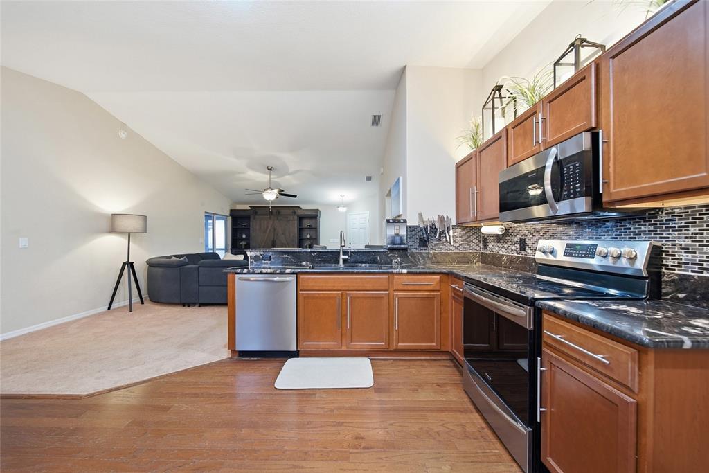 4066 Sundance Pl Loop Mulberry, FL 33860 - Photo 9 of 28 a open kitchen with stainless steel appliances granite countertop a stove top oven a sink dishwasher a dining table and chairs with wooden floor