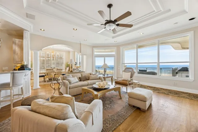 a living room with furniture large windows and wooden floor