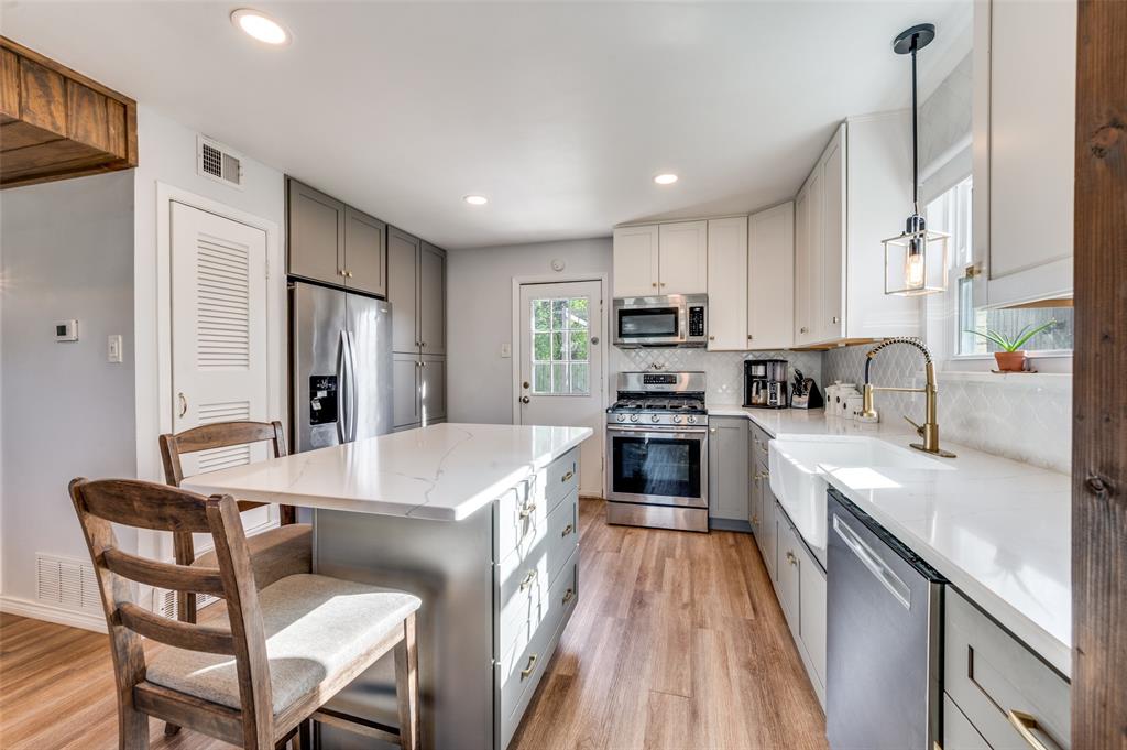 2924 West 11th Street Irving, TX 75060 - Photo 10 of 39 a kitchen with kitchen island a stove a sink a refrigerator a dining table and chairs