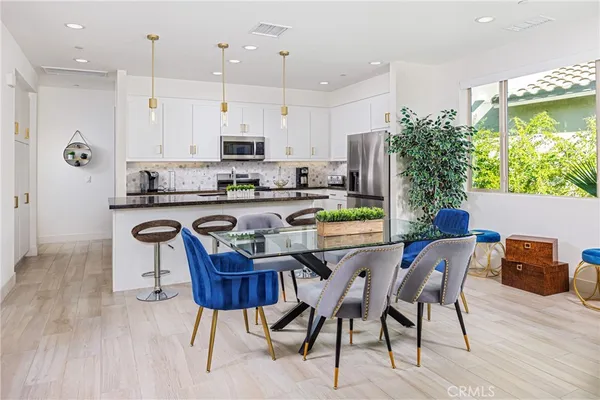 a kitchen with stainless steel appliances granite countertop a table chairs in it and wooden floors