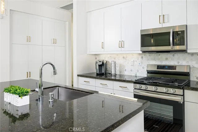 a kitchen with stainless steel appliances granite countertop a stove a microwave and a sink
