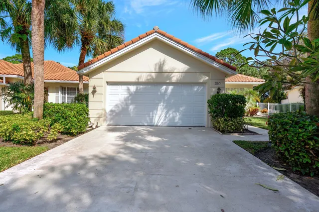 a view of a white house with a yard and palm trees