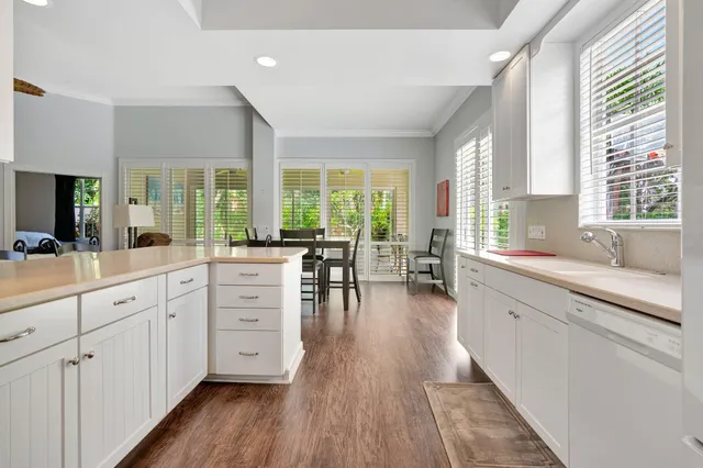 a large kitchen with white cabinets and wooden floor