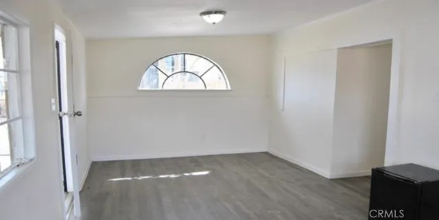 an empty room with wooden floor mirror and windows