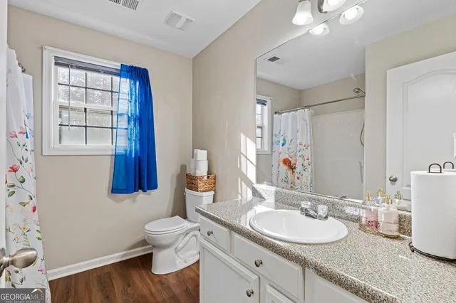 a bathroom with a granite countertop sink mirror vanity and toilet
