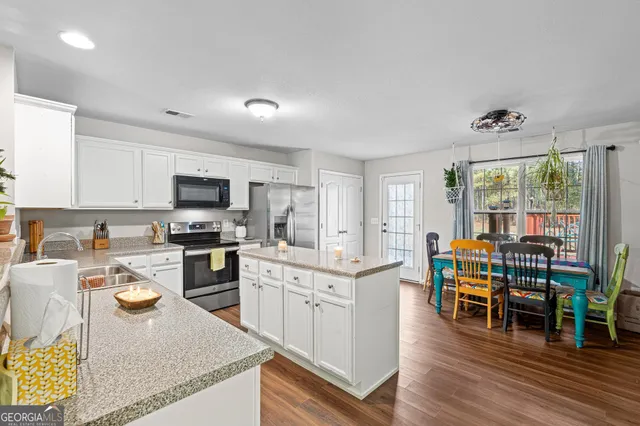 a kitchen with stainless steel appliances granite countertop a stove top oven a sink dishwasher and a dining table with wooden floor