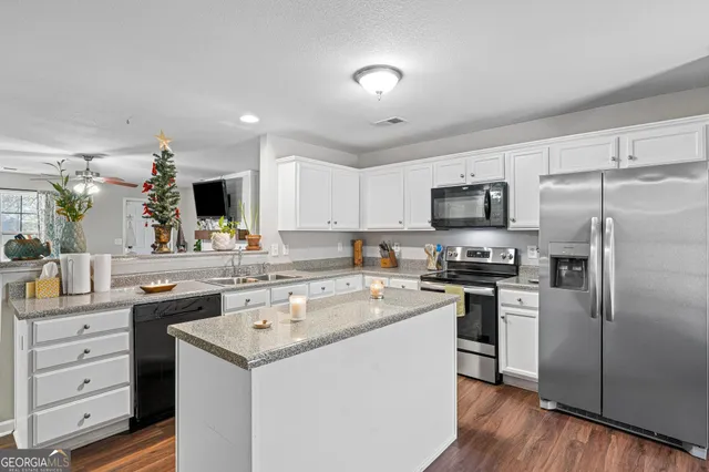 a kitchen that has a sink a counter top space stainless steel appliances and cabinets