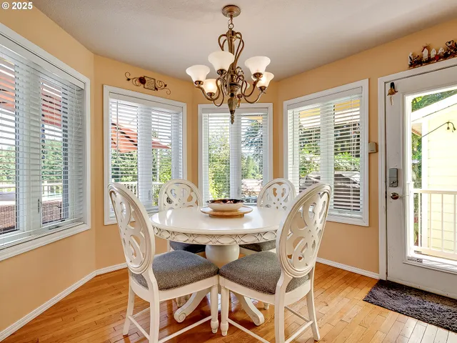 a dining room with wooden floor a chandelier a glass table and chairs