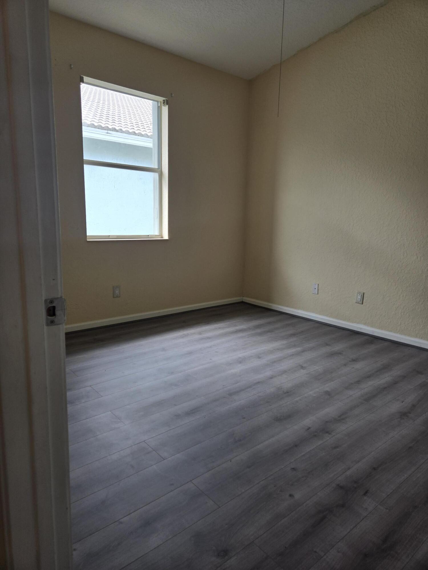 3141 Laurel Ridge Circle Riviera Beach, FL 33404 - Photo 11 of 16 an empty room with wooden floor and windows