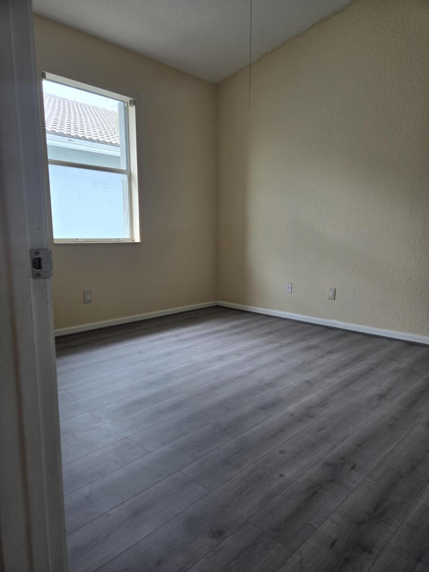 3141 Laurel Ridge Circle Riviera Beach, FL 33404 - Photo 14 of 16 an empty room with wooden floor and windows