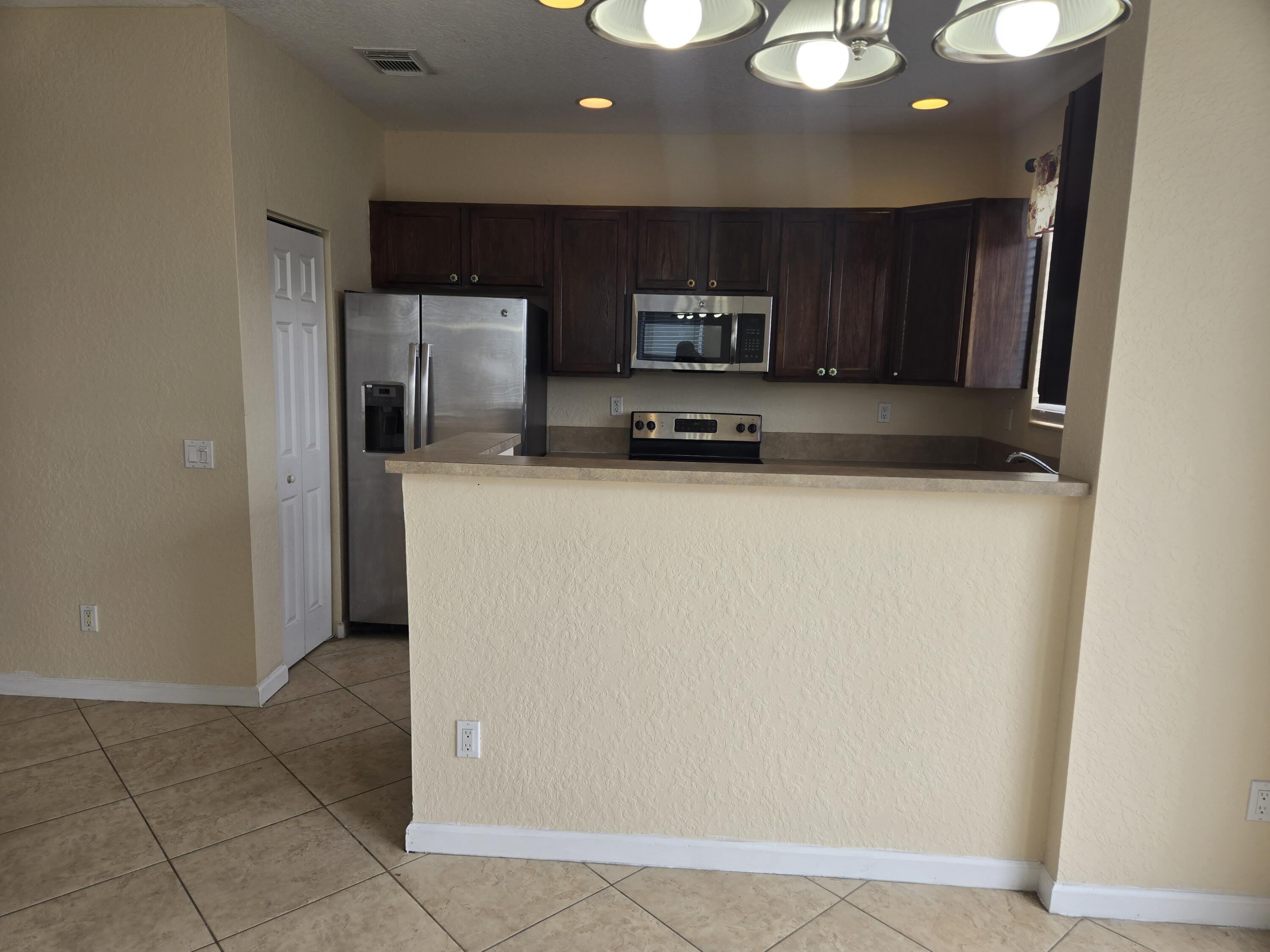 3141 Laurel Ridge Circle Riviera Beach, FL 33404 - Photo 3 of 16 a kitchen with stainless steel appliances a refrigerator and a stove top oven