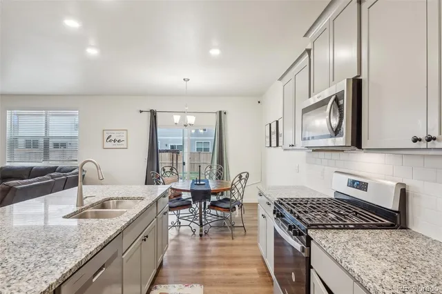 a kitchen with granite countertop stainless steel appliances a sink stove top oven and cabinets