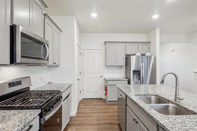 a kitchen with stainless steel appliances granite countertop a sink stove and refrigerator