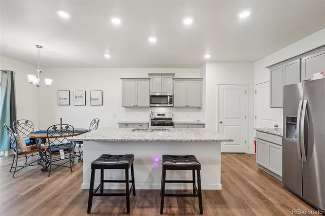 a kitchen with stainless steel appliances granite countertop a dining table chairs refrigerator sink and cabinets