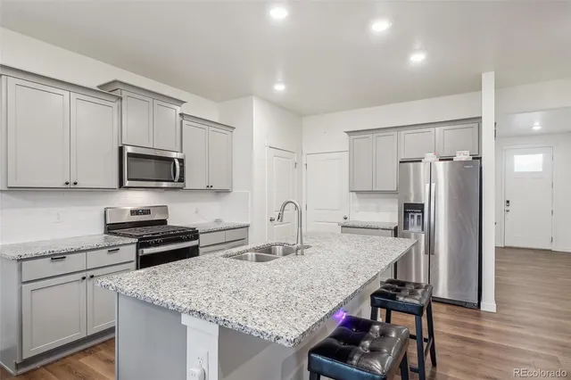 a kitchen with stainless steel appliances granite countertop a sink stove microwave and refrigerator