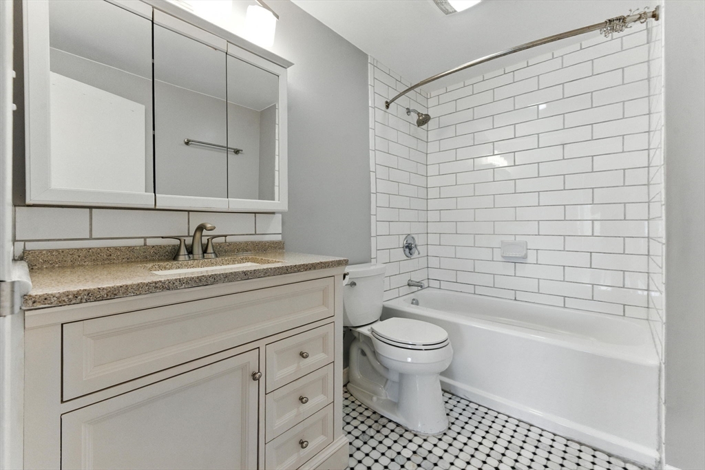 22 Chestnut Place, Unit 608 Brookline, MA 02445 - Photo 15 of 29 a bathroom with a granite countertop sink a toilet and bathtub